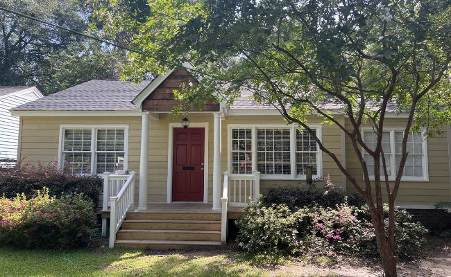 Front view of home after vinyl siding installation with yellow siding and red front door.
