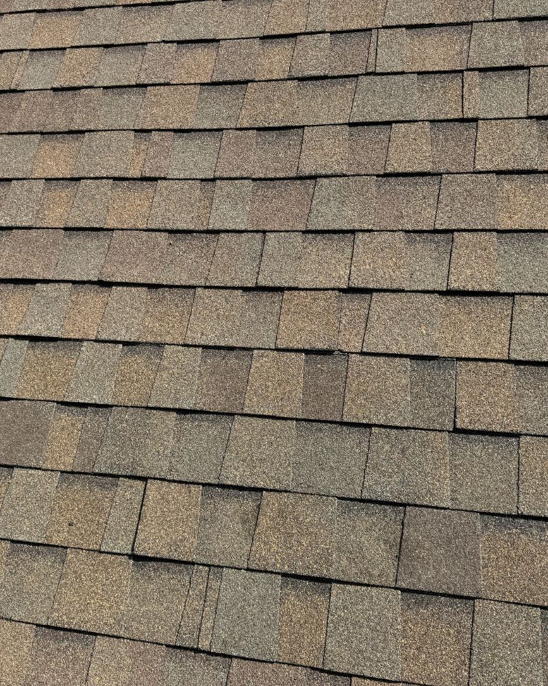 Close-up of new asphalt shingle roof in mixed brown tones.