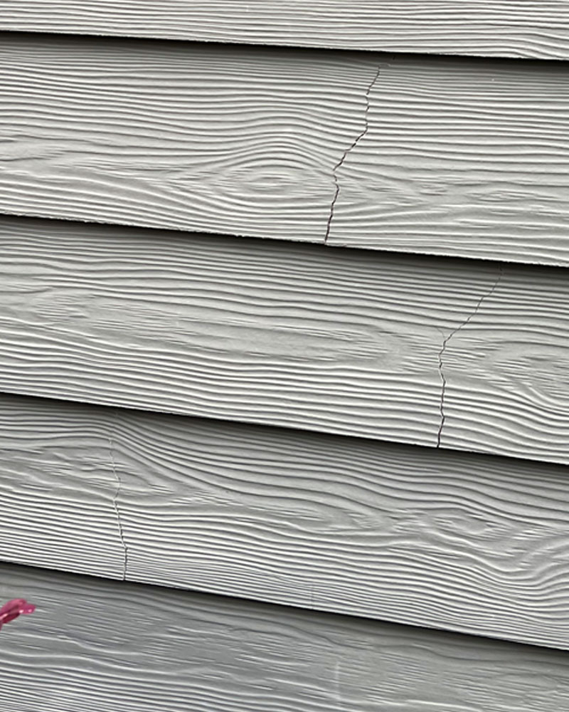 Cracked fiber cement siding panels showing visible fractures.