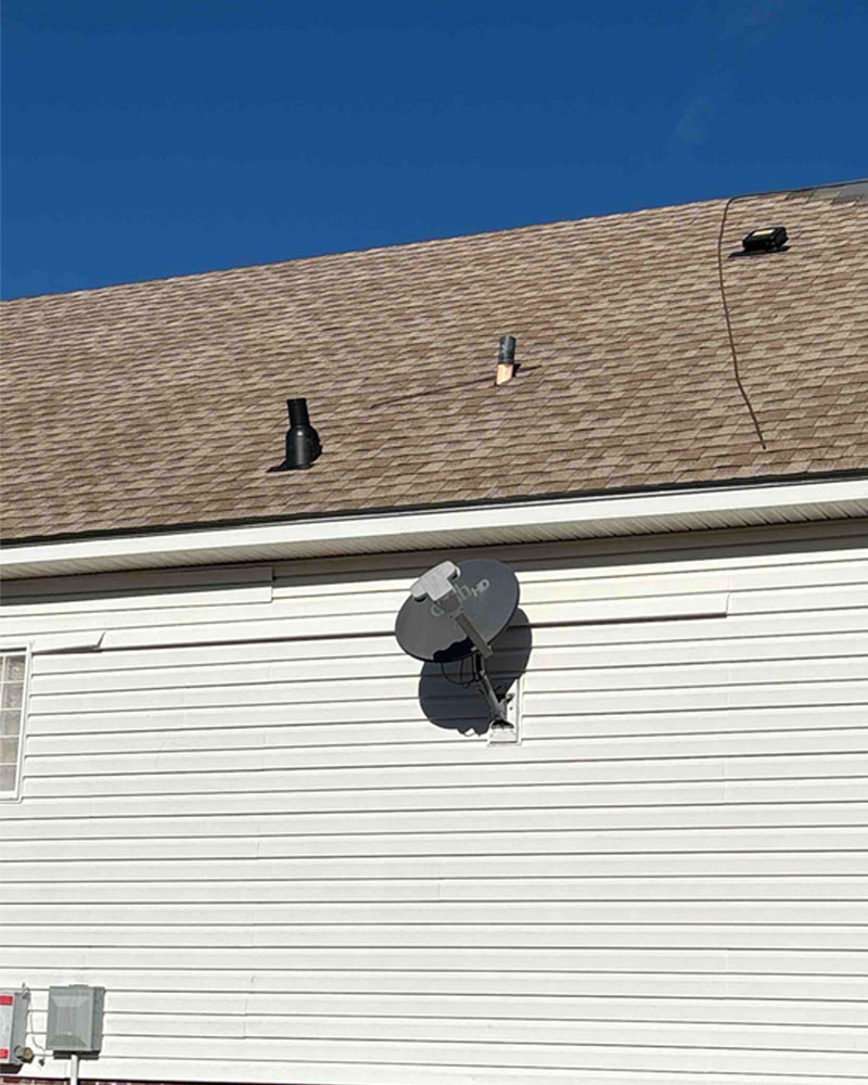 Close view of torn shingles and exposed roof decking on a residential roof.