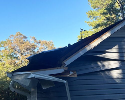 storm-damaged-siding-repaired-near-me-south-carolina Damaged roof with collapsed gable and torn shingles before roof repair.