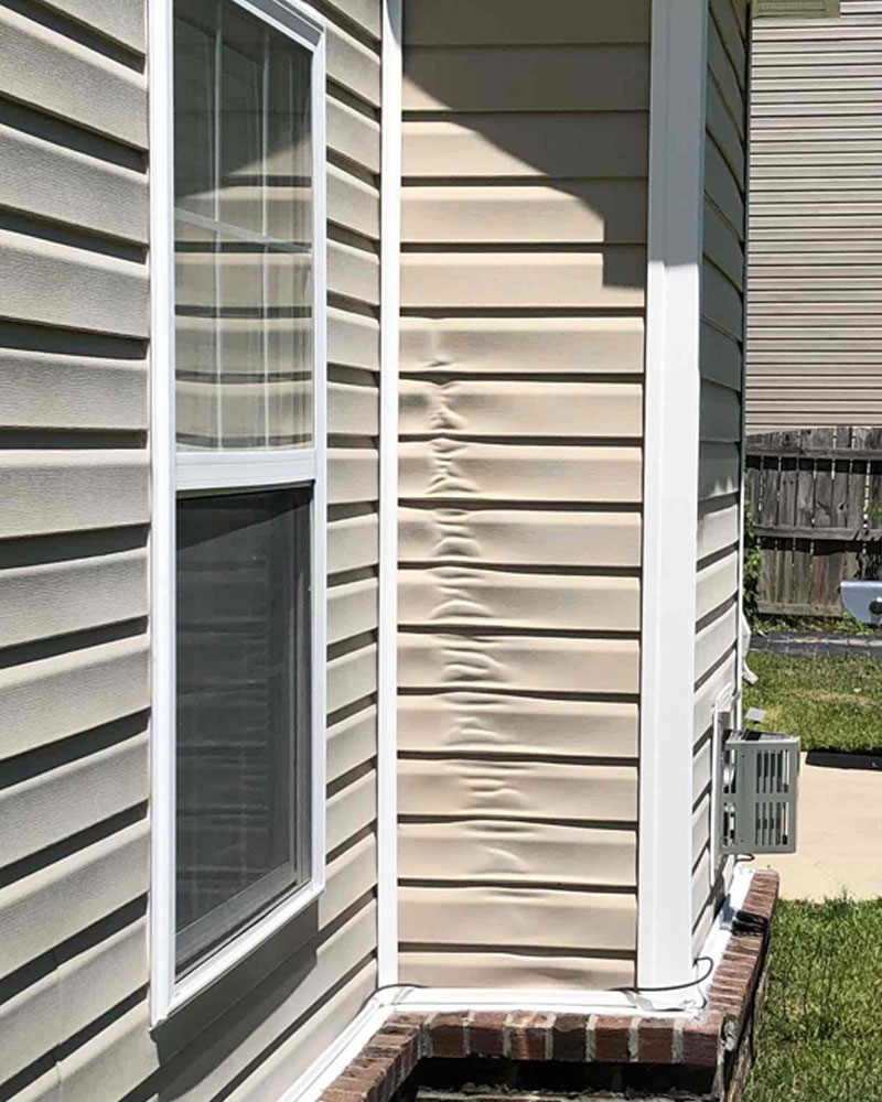 Heat-warped vinyl siding on a home’s exterior corner wall.