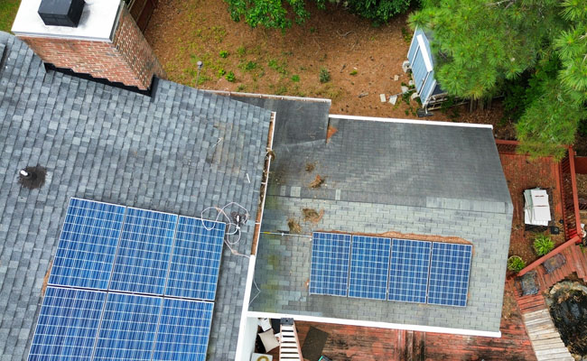 Roof with solar panels and visible shingle wear.